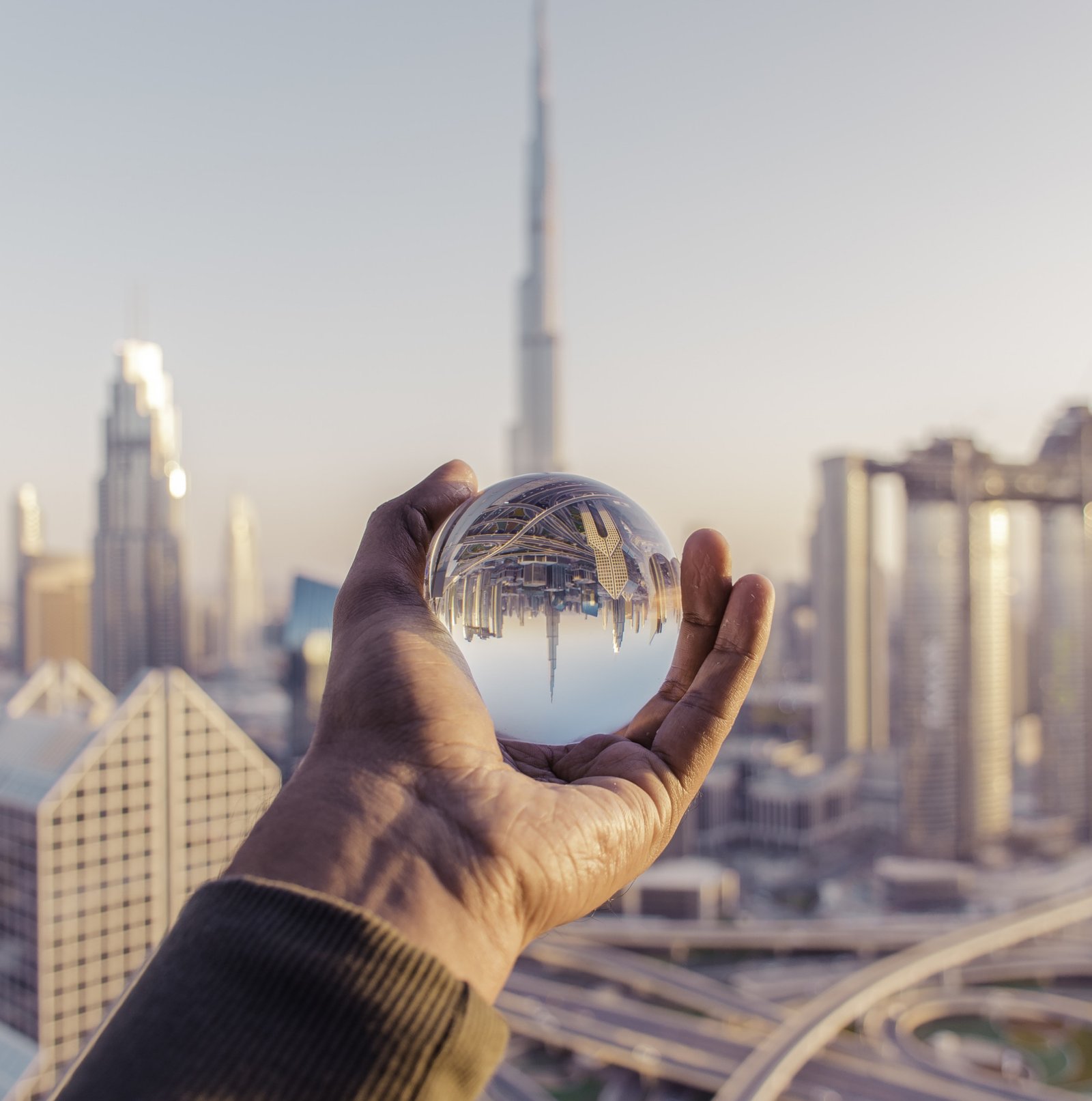 closeup-shot-male-hand-holding-crystal-ball-with-reflection-city